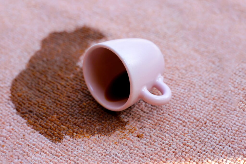 Coffee spilled from white cup on the carpet